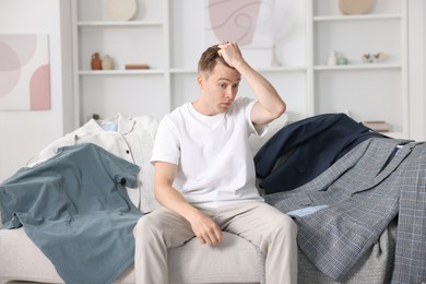 Photo of Getting ready. Stressed young man choosing clothes at home