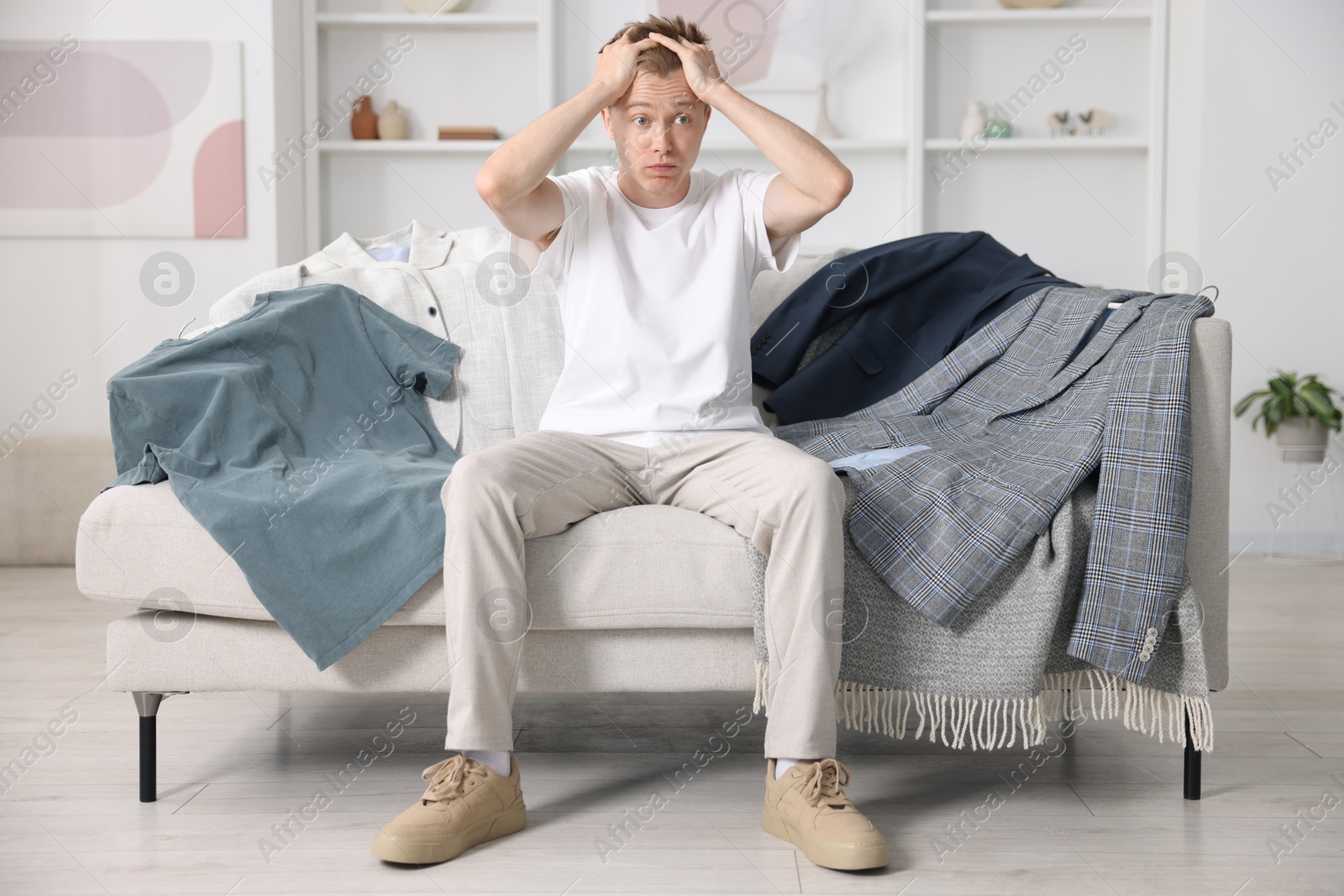 Photo of Getting ready. Stressed young man choosing clothes at home