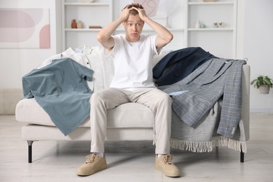 Photo of Getting ready. Stressed young man choosing clothes at home