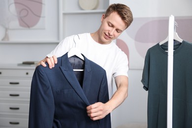 Photo of Getting ready. Young man choosing clothes at home