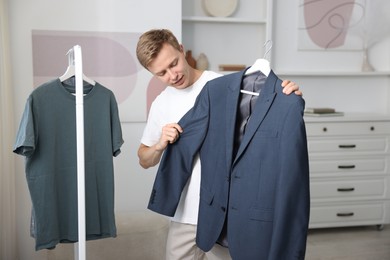 Photo of Getting ready. Young man choosing clothes at home