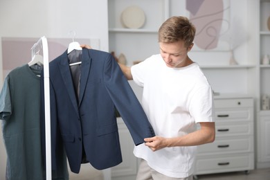 Photo of Getting ready. Young man choosing clothes at home