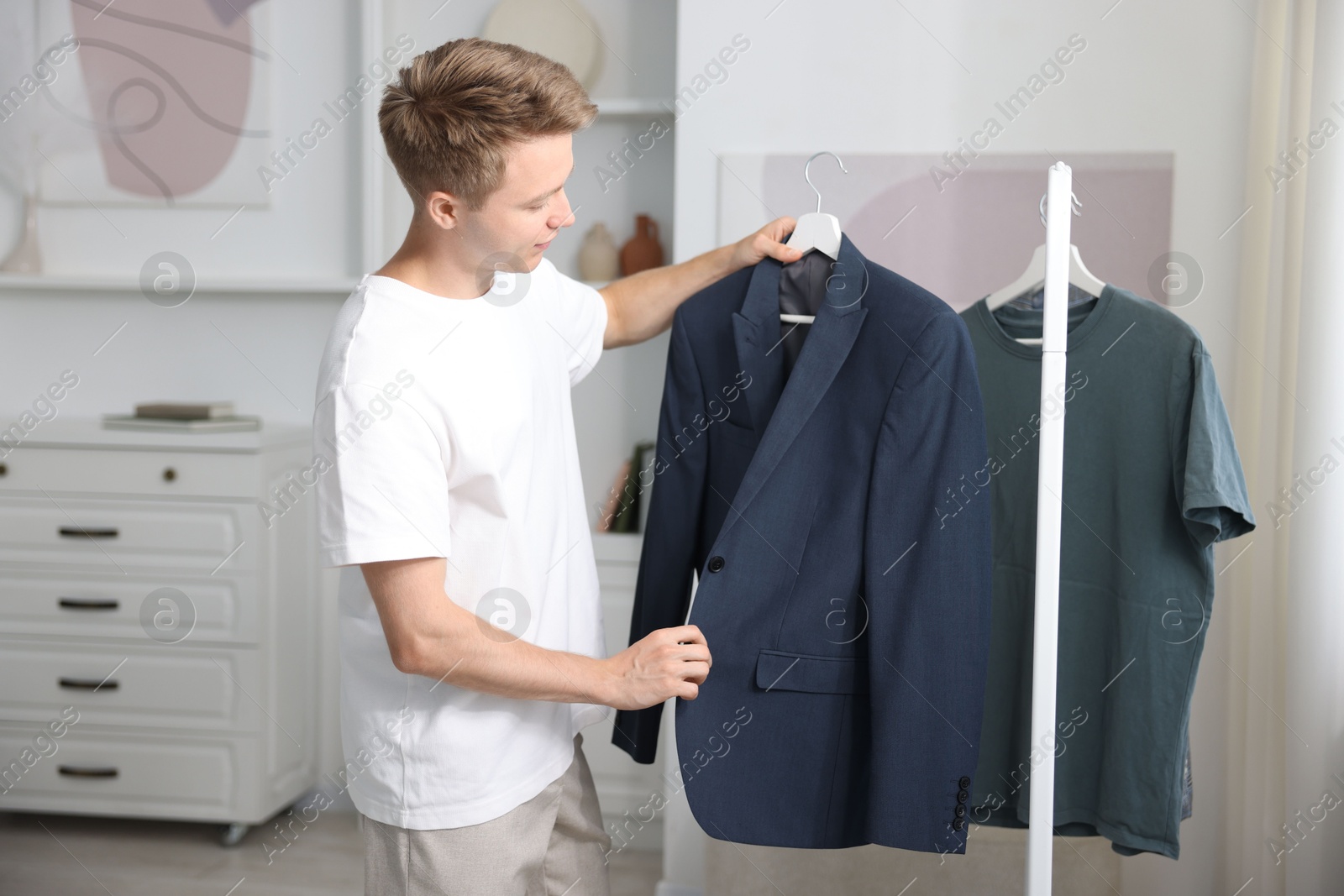 Photo of Getting ready. Young man choosing clothes at home