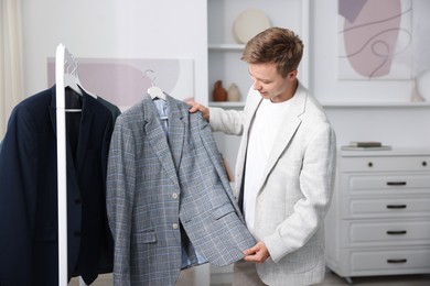 Photo of Getting ready. Young man choosing clothes at home