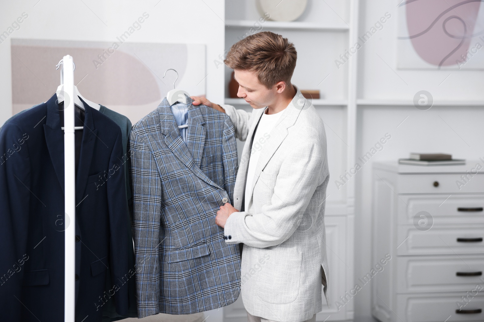 Photo of Getting ready. Young man choosing clothes at home