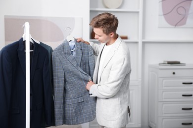 Photo of Getting ready. Young man choosing clothes at home