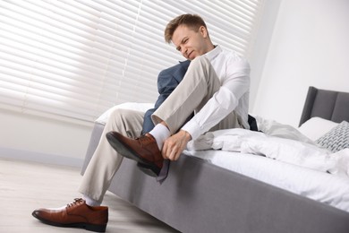 Photo of Getting ready. Young man putting on stylish shoes at home