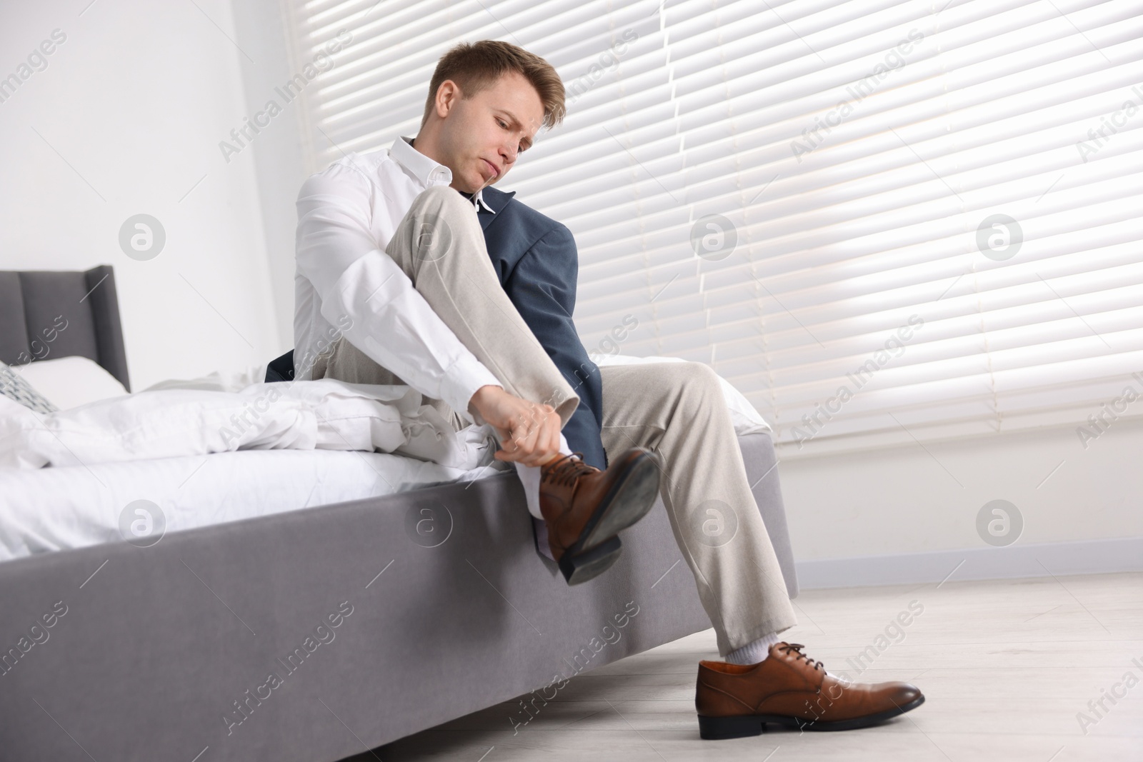 Getting ready. Young man putting on stylish shoes at home Photo of Getting ready. Young man putting on stylish shoes at home