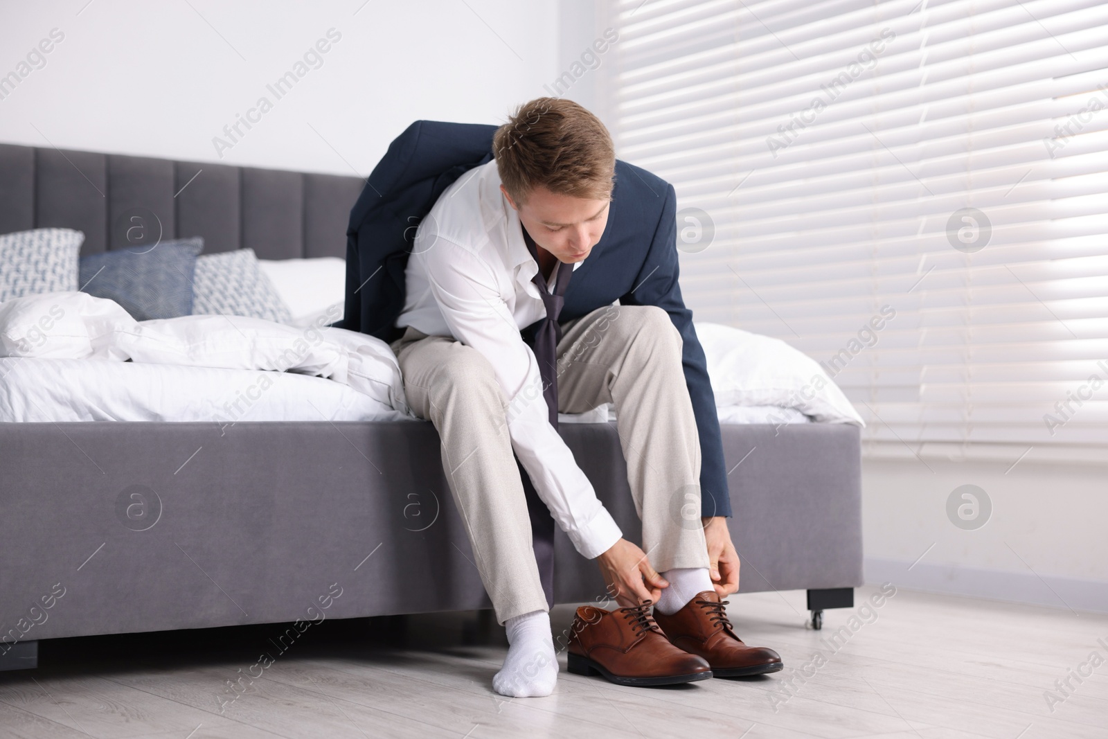 Getting ready. Young man putting on stylish shoes at home Photo of Getting ready. Young man putting on stylish shoes at home