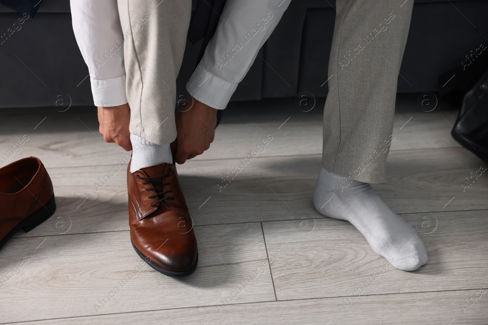 Photo of Getting ready. Young man putting on stylish shoes at home, closeup