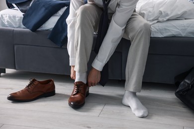 Photo of Getting ready. Young man putting on stylish shoes at home, closeup