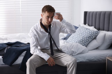 Photo of Sad young man with cup of coffee getting ready at home