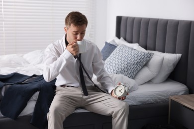 Photo of Sad young man with cup of coffee getting ready at home