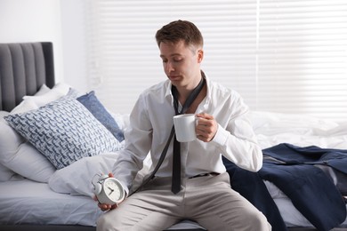 Photo of Sad young man with cup of coffee getting ready at home
