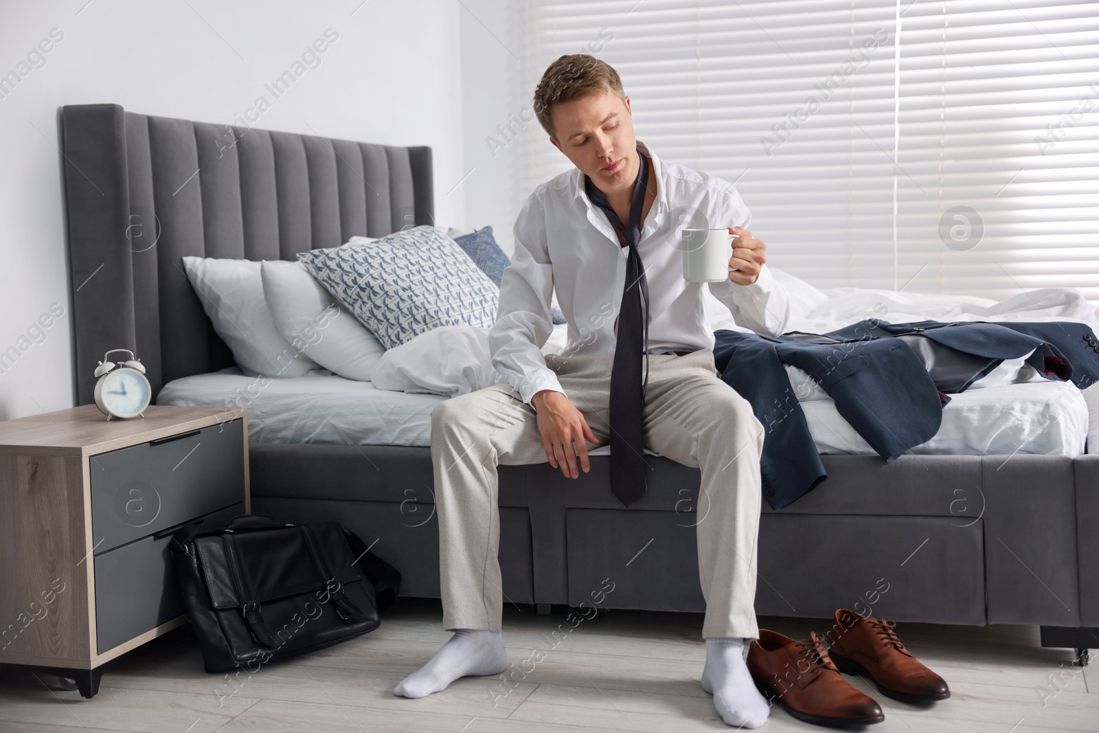 Sad young man with cup of coffee getting ready at home Photo of Sad young man with cup of coffee getting ready at home
