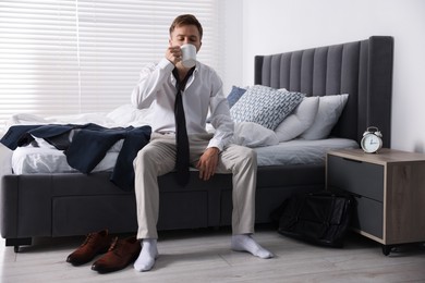 Photo of Sad young man with cup of coffee getting ready at home
