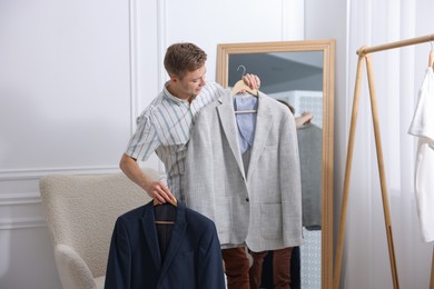 Photo of Getting ready. Young man choosing clothes at home