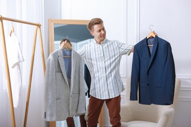 Photo of Getting ready. Young man choosing clothes at home