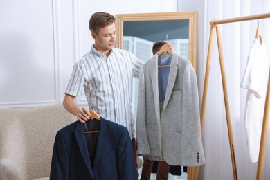 Photo of Getting ready. Young man choosing clothes at home