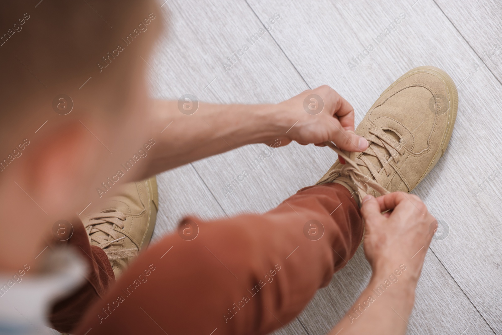Photo of Getting ready. Young man putting on stylish shoes at home, above view