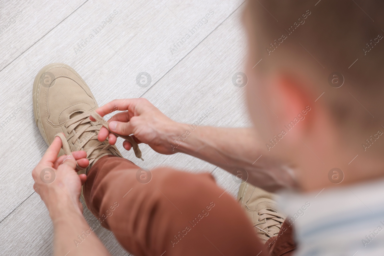 Getting ready. Young man putting on stylish shoes at home, above view Photo of Getting ready. Young man putting on stylish shoes at home, above view