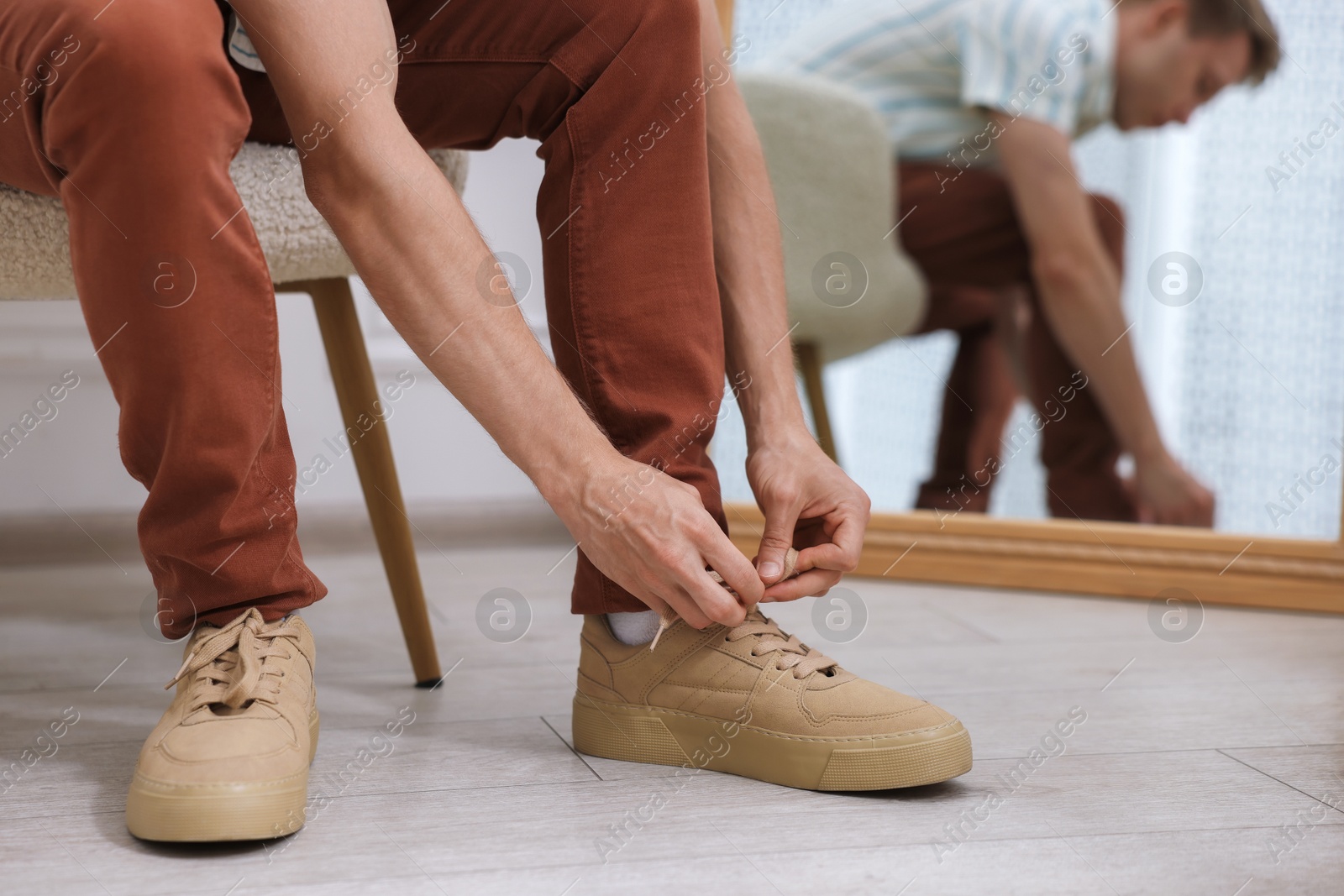 Photo of Getting ready. Young man putting on stylish shoes at home, closeup