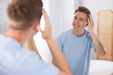Photo of Young man getting ready near mirror at home