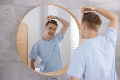 Photo of Young man getting ready near mirror at home