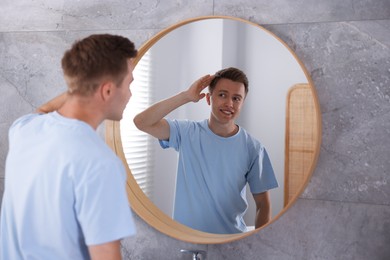 Photo of Young man getting ready near mirror at home