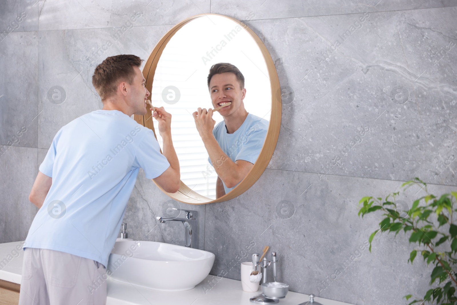 Getting ready. Young man brushing his teeth near mirror at home Photo of Getting ready. Young man brushing his teeth near mirror at home