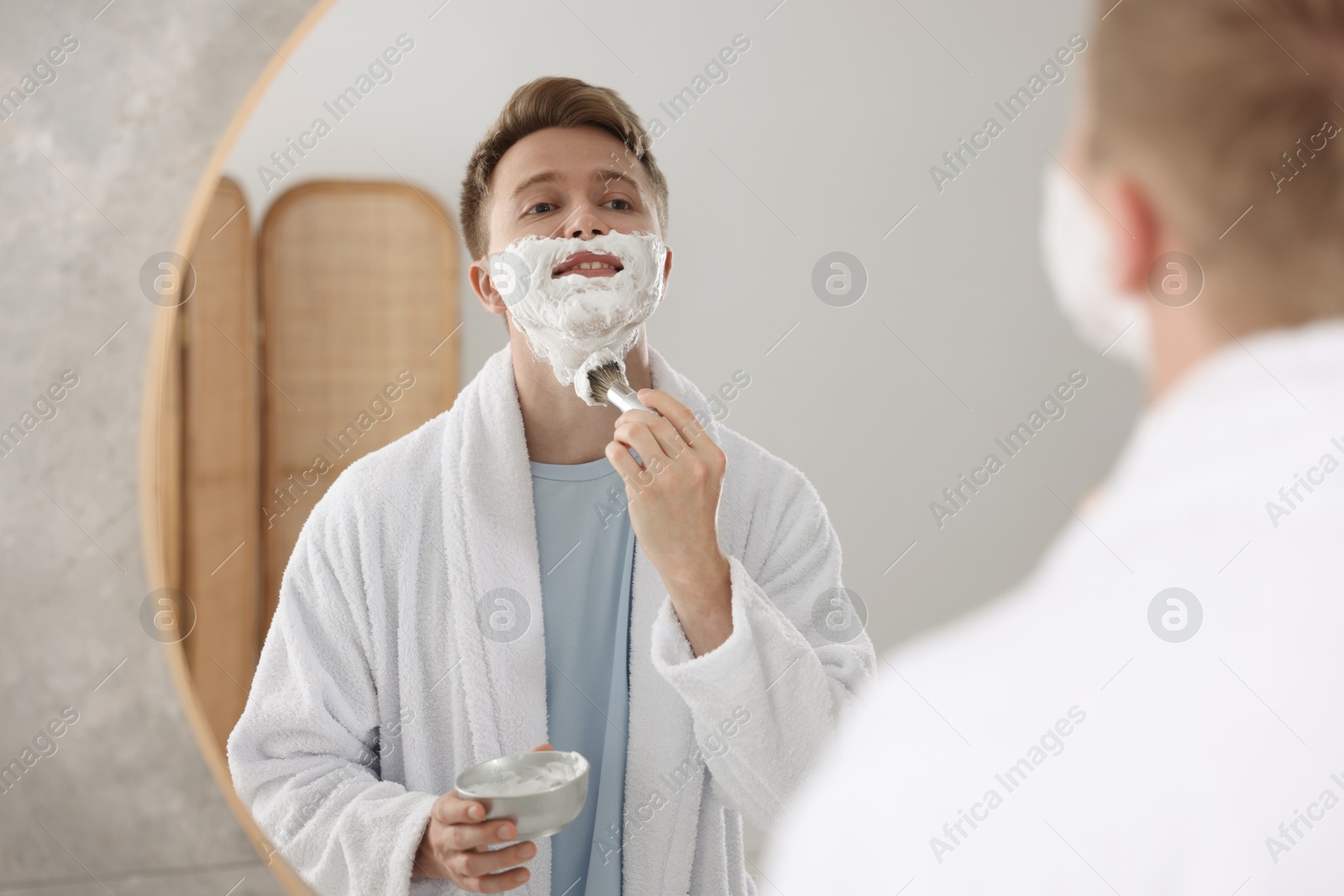 Getting ready. Young man shaving with cream near mirror at home Photo of Getting ready. Young man shaving with cream near mirror at home