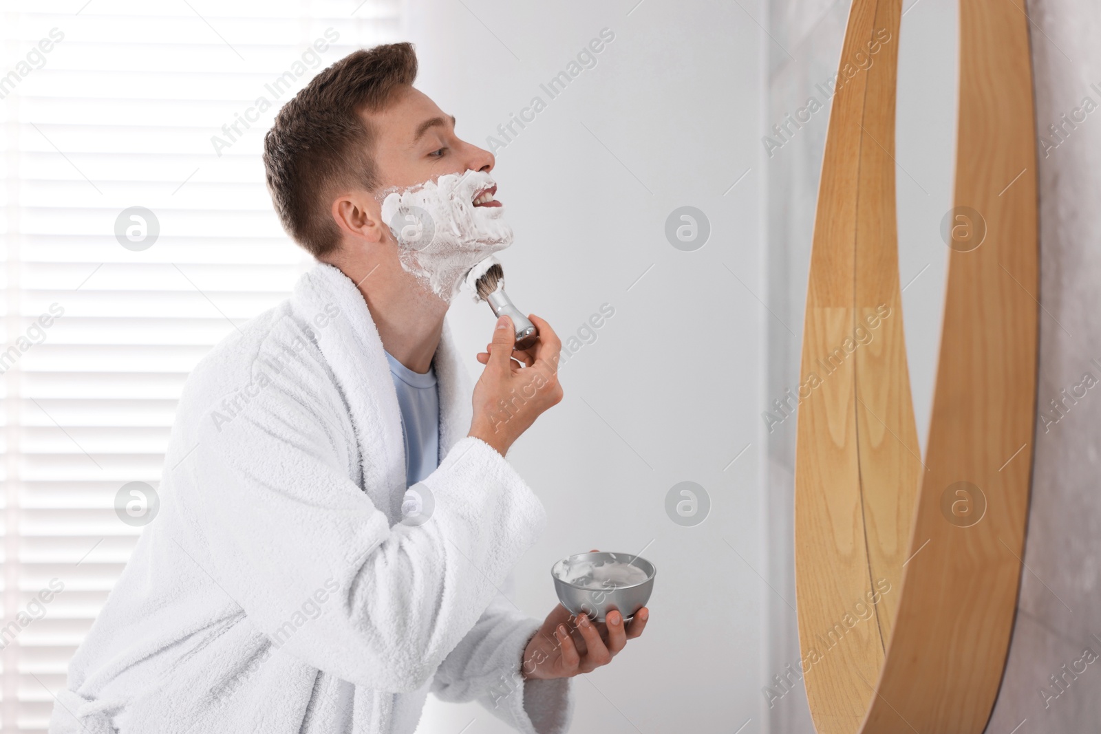 Getting ready. Young man shaving with cream near mirror at home Photo of Getting ready. Young man shaving with cream near mirror at home