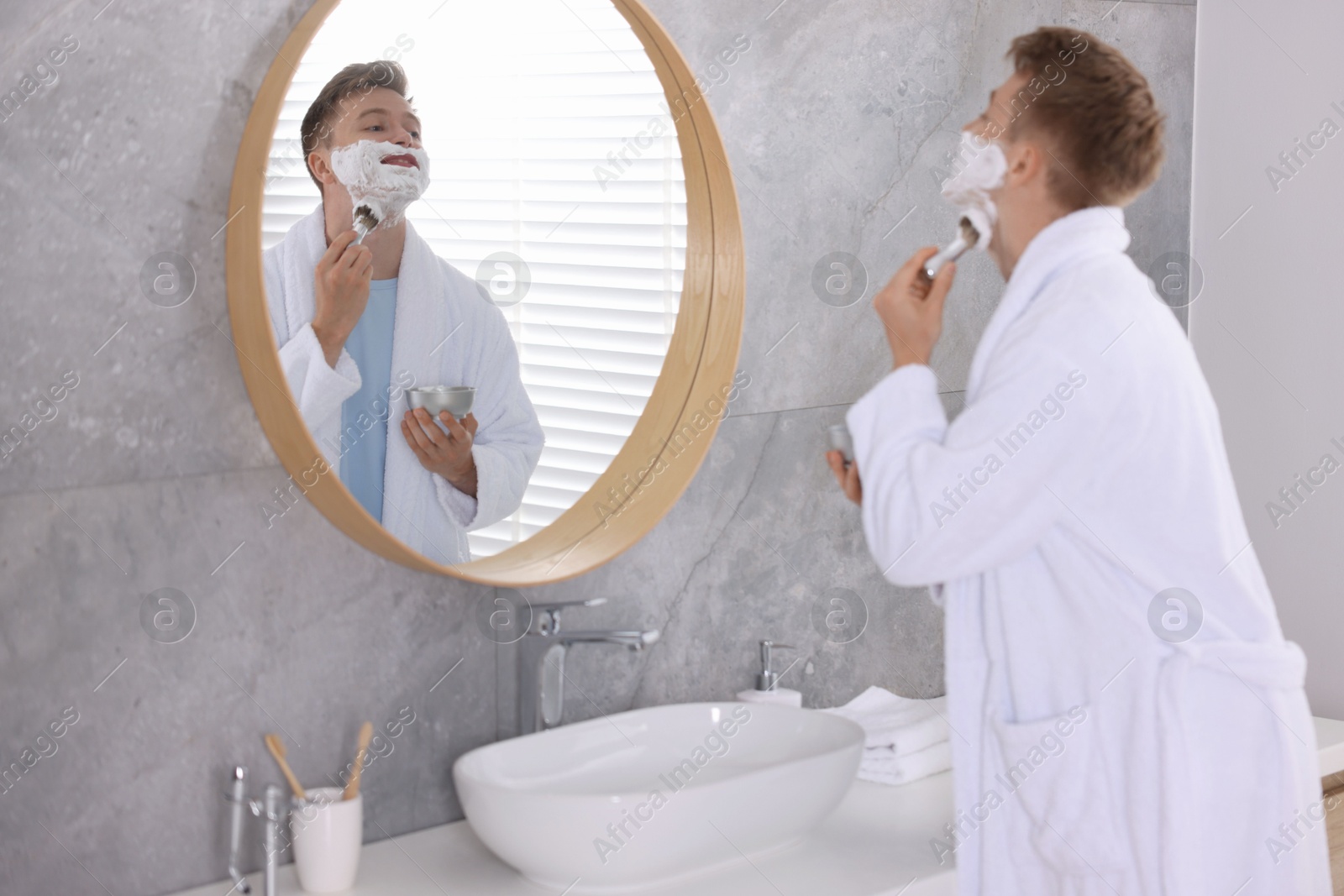 Getting ready. Young man shaving with cream near mirror at home Photo of Getting ready. Young man shaving with cream near mirror at home