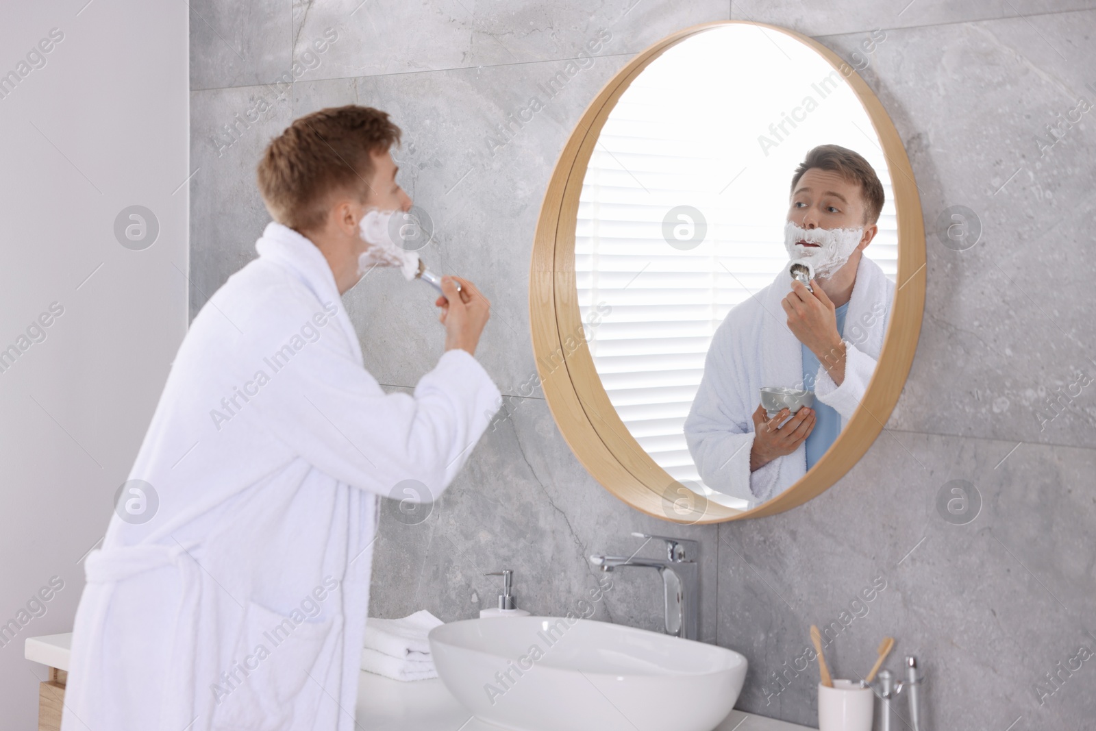 Getting ready. Young man shaving with cream near mirror at home Photo of Getting ready. Young man shaving with cream near mirror at home