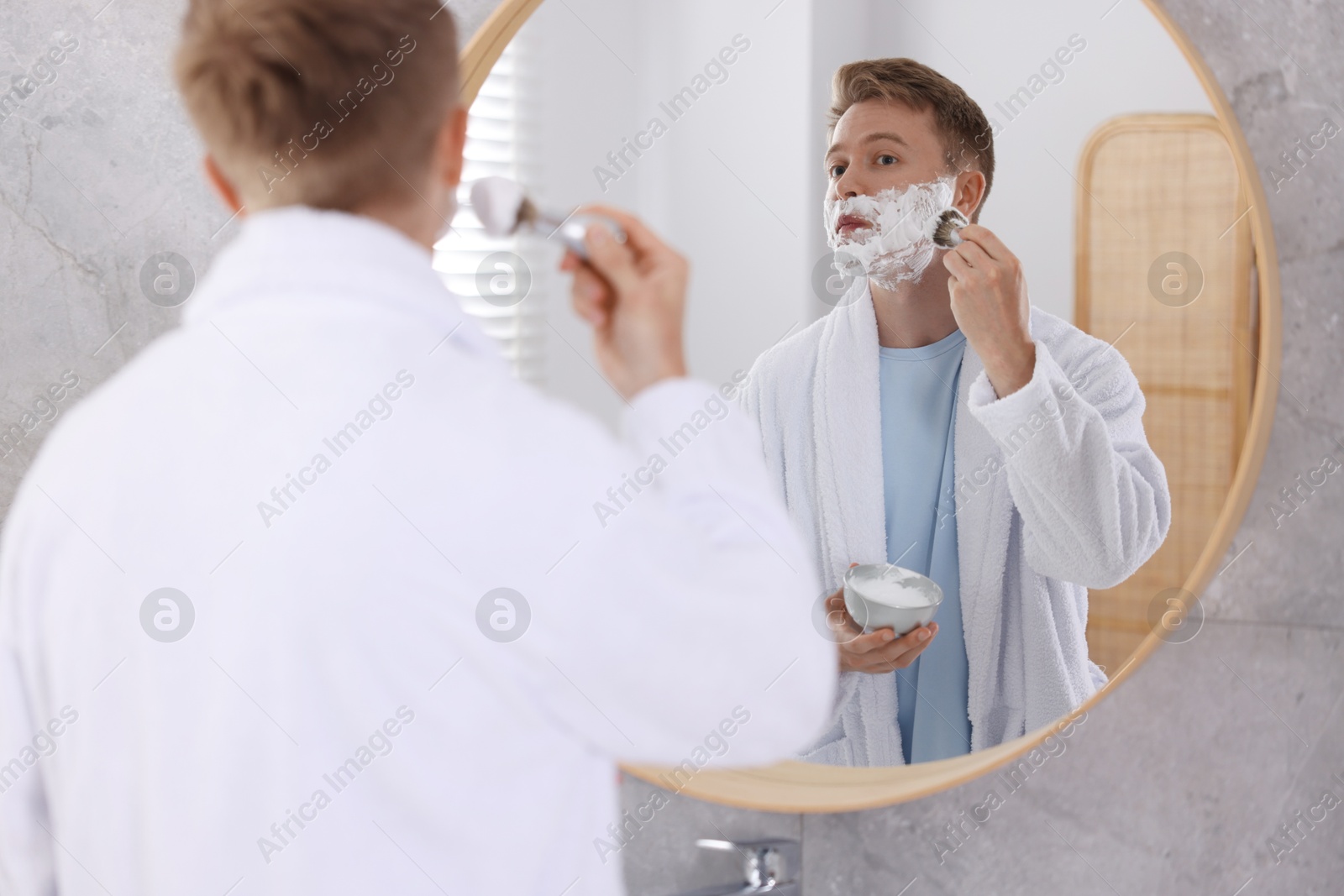 Getting ready. Young man shaving with cream near mirror at home Photo of Getting ready. Young man shaving with cream near mirror at home