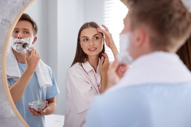 Photo of Young couple getting ready together near mirror at home