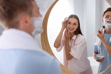 Photo of Young couple getting ready together near mirror at home