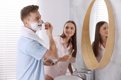 Photo of Young couple getting ready together near mirror at home