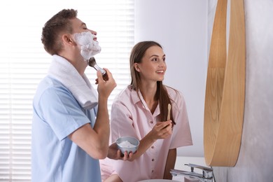 Photo of Young couple getting ready together near mirror at home