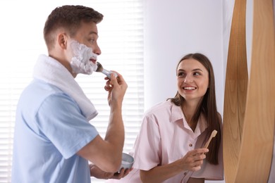 Photo of Young couple getting ready together near mirror at home