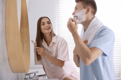 Photo of Young couple getting ready together near mirror at home