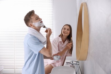 Photo of Young couple getting ready together near mirror at home
