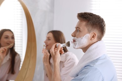 Photo of Young couple getting ready together near mirror at home