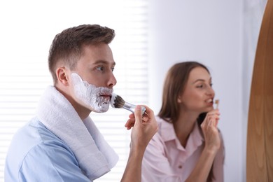 Photo of Young couple getting ready together near mirror at home