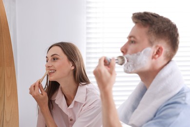 Photo of Young couple getting ready together near mirror at home