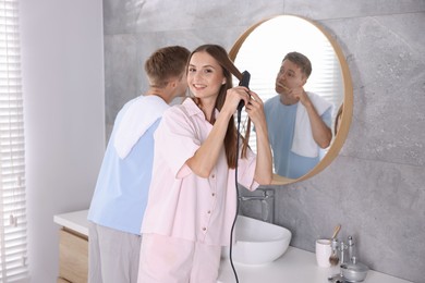 Photo of Young couple getting ready together near mirror at home