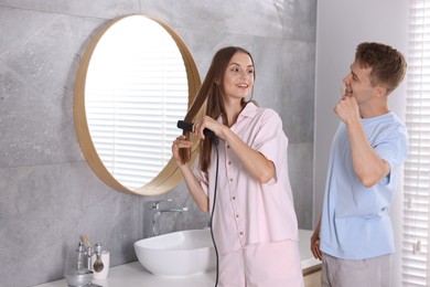Photo of Young couple getting ready together near mirror at home