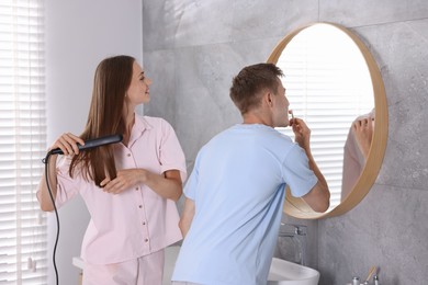 Photo of Young couple getting ready together near mirror at home