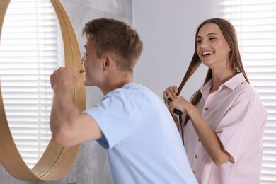 Photo of Young couple getting ready together near mirror at home