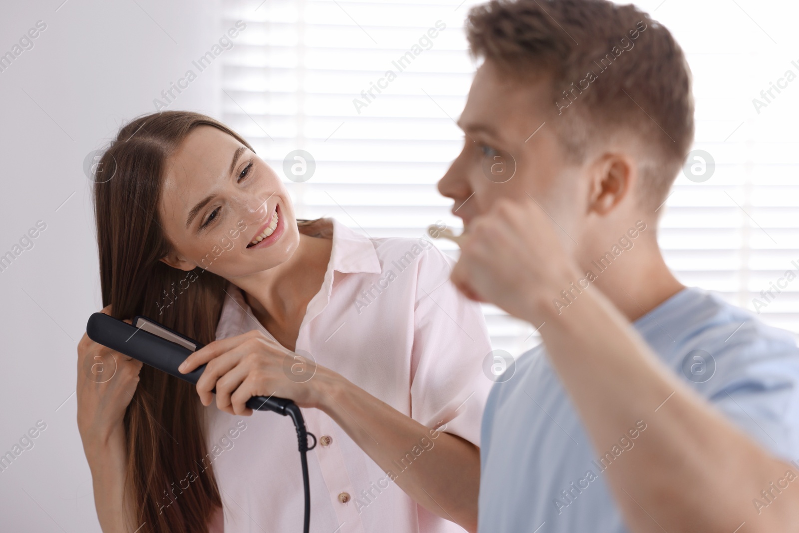Photo of Young couple getting ready together near mirror at home
